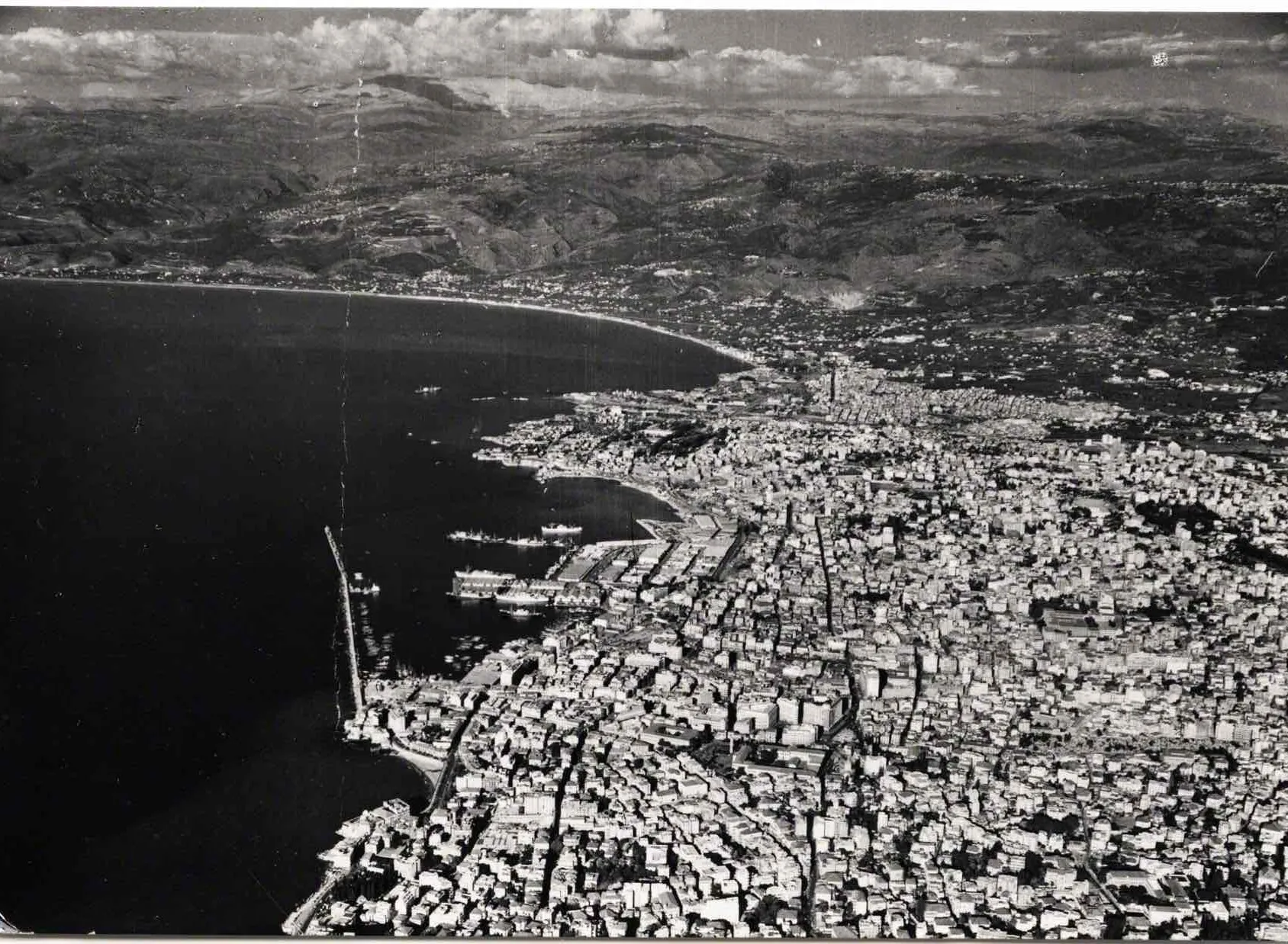 Black-and-white aerial photograph of Beirut, its harbor and dense rooftops meeting the sea