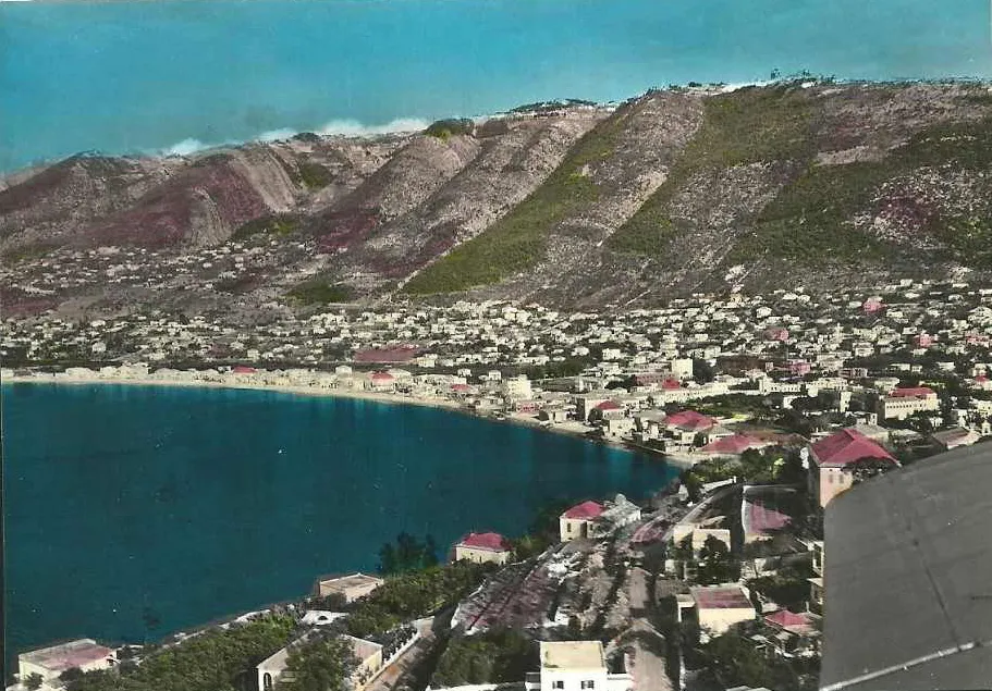 Hand-tinted postcard of a Lebanese coastal bay beneath terraced mountains
