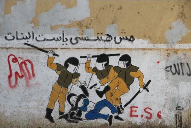 Graffiti on a wall: three riot police beat a figure on the ground, an Arabic caption above.