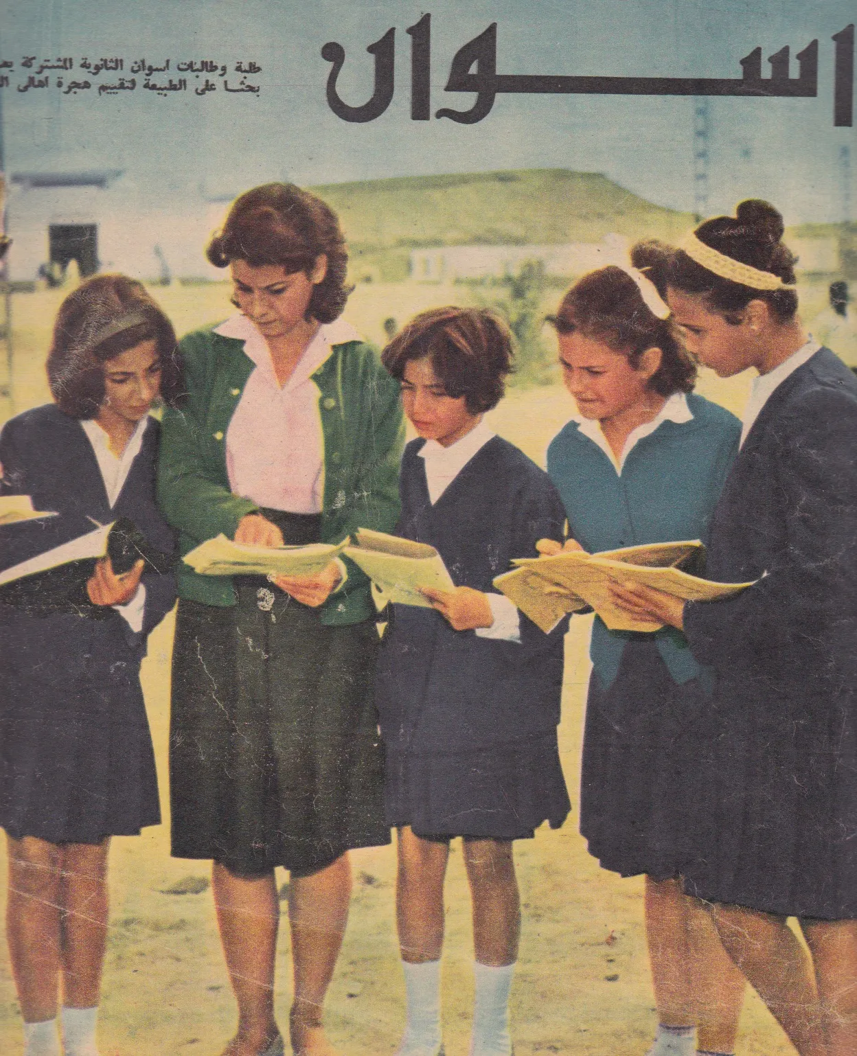 Magazine page headed Aswan in Arabic: five schoolgirls in uniform read from books outdoors.